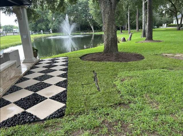 Checkerboard pavers and new sod by a pond